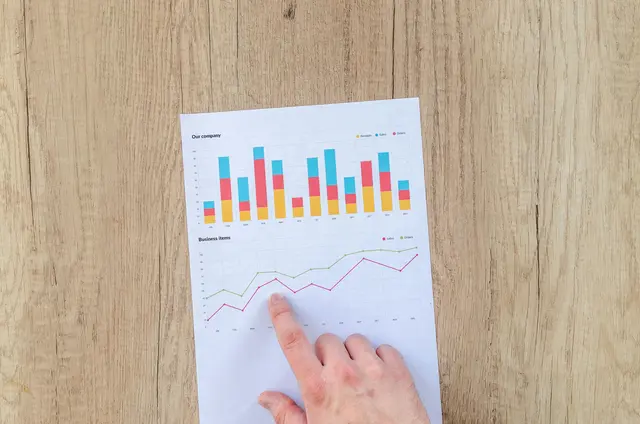 Finger pointing at a sheet of paper on a table containing charts