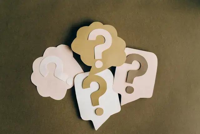 4 question mark paper cutouts pasted on paper shaped like speech bubbles placed on a table
